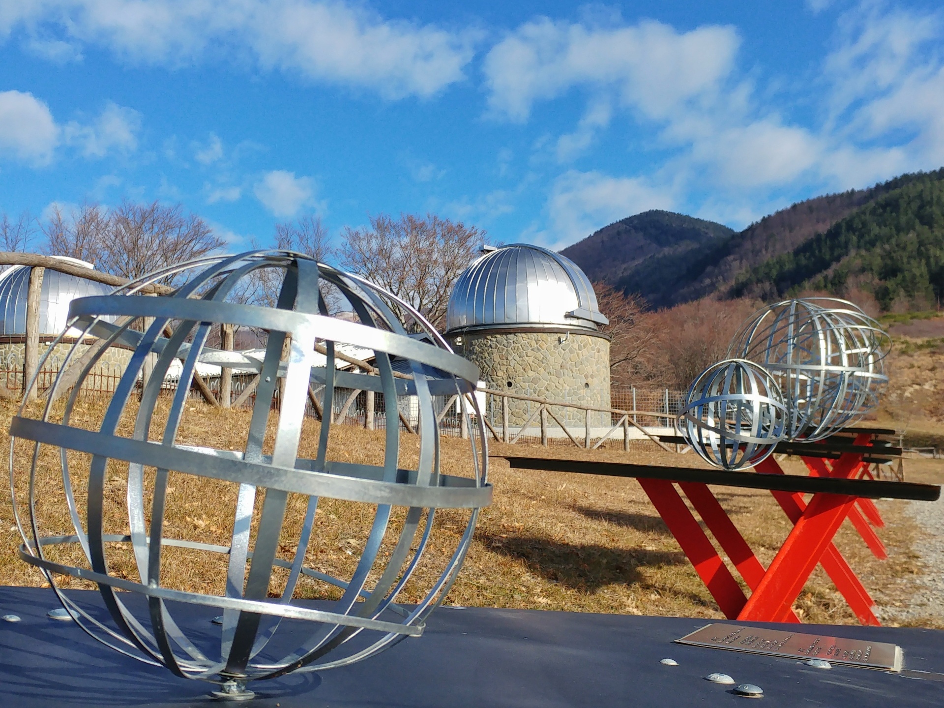 Some of the manufactured sculptures of the Stars Park representing the planets and, in the distance, the Pistoia Mountains Astronomical Observatory.